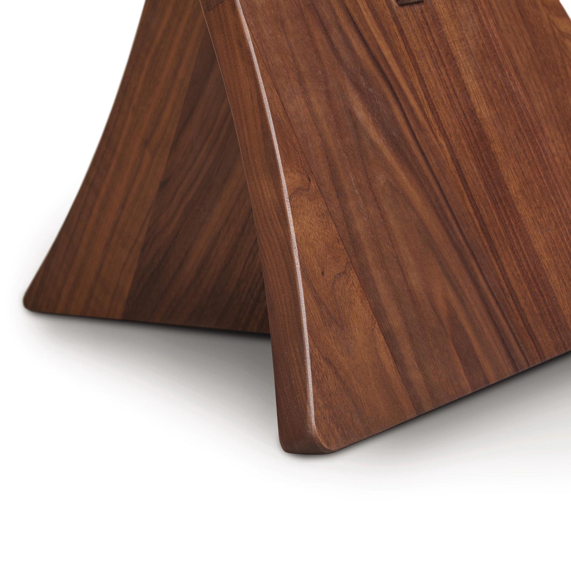 Copeland Planes Round Glass Top End Table with elegantly curved walnut base and rich wood grain, showcasing fine craftsmanship.
