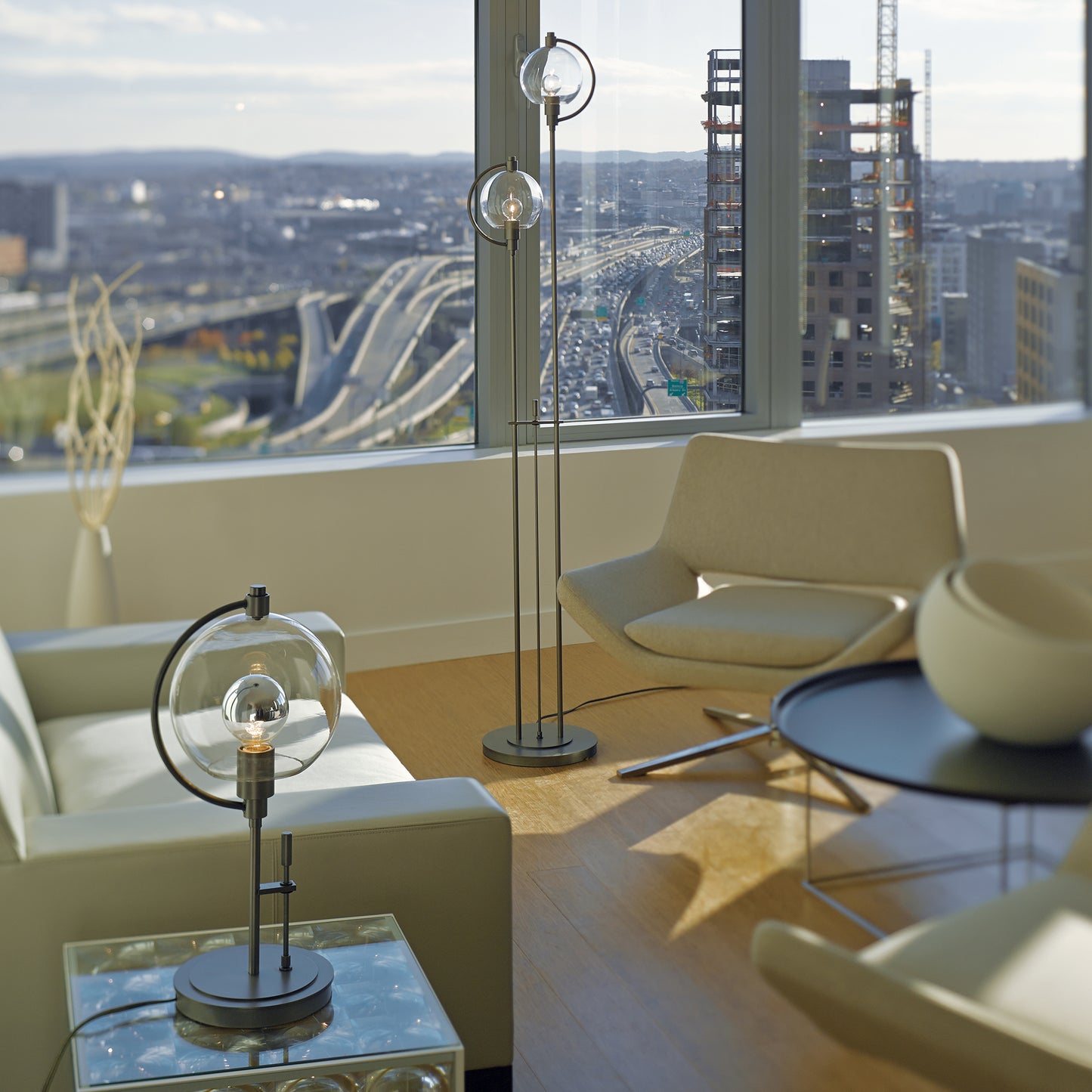 Contemporary lounge featuring modern wood chairs and table, highlighted by a Hubbardton Forge Pluto Table Lamp, all crafted with fine Vermont woodworking.