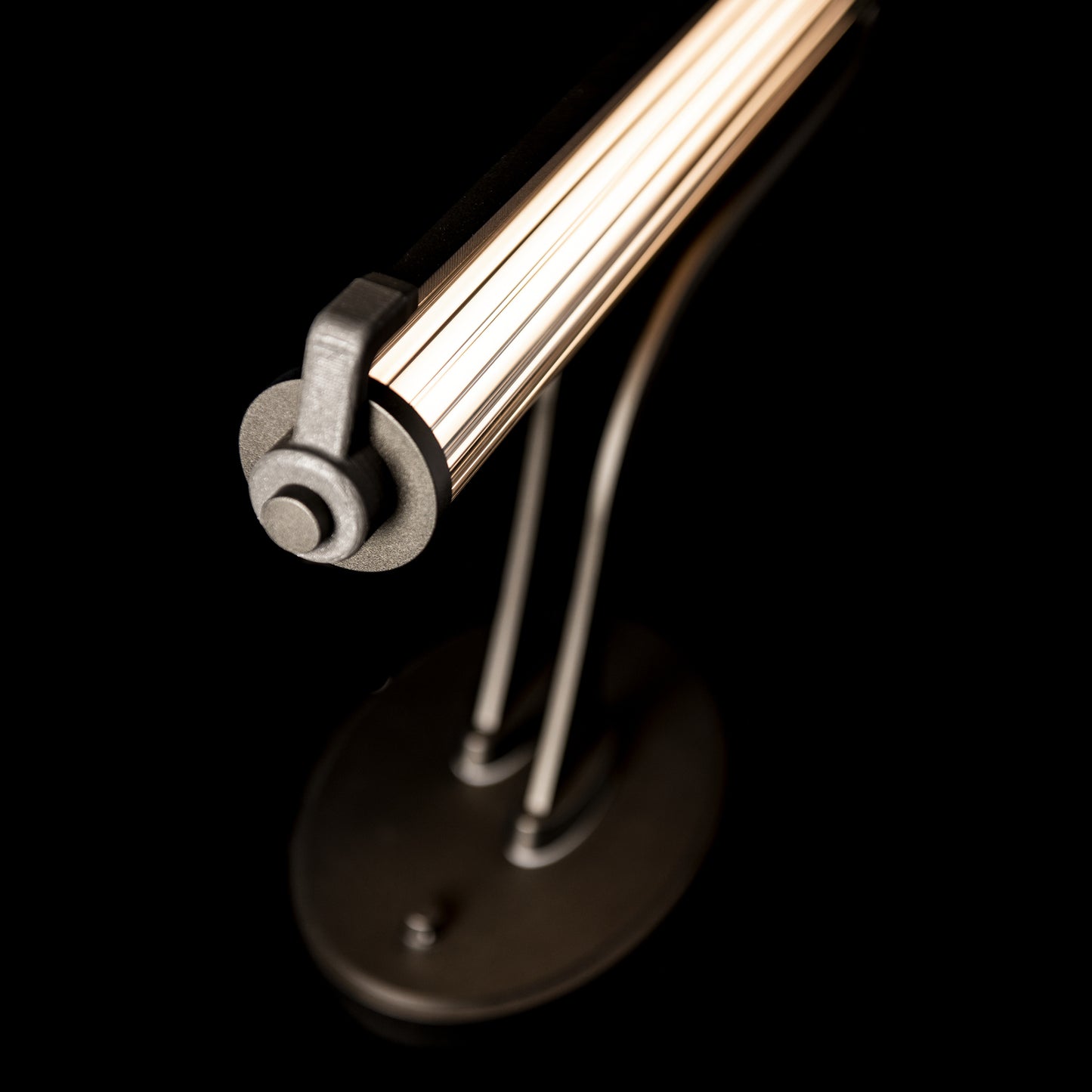 Hubbardton Forge Pulse Table Lamp highlighting its sleek cylindrical light bar and elegant curved rods.