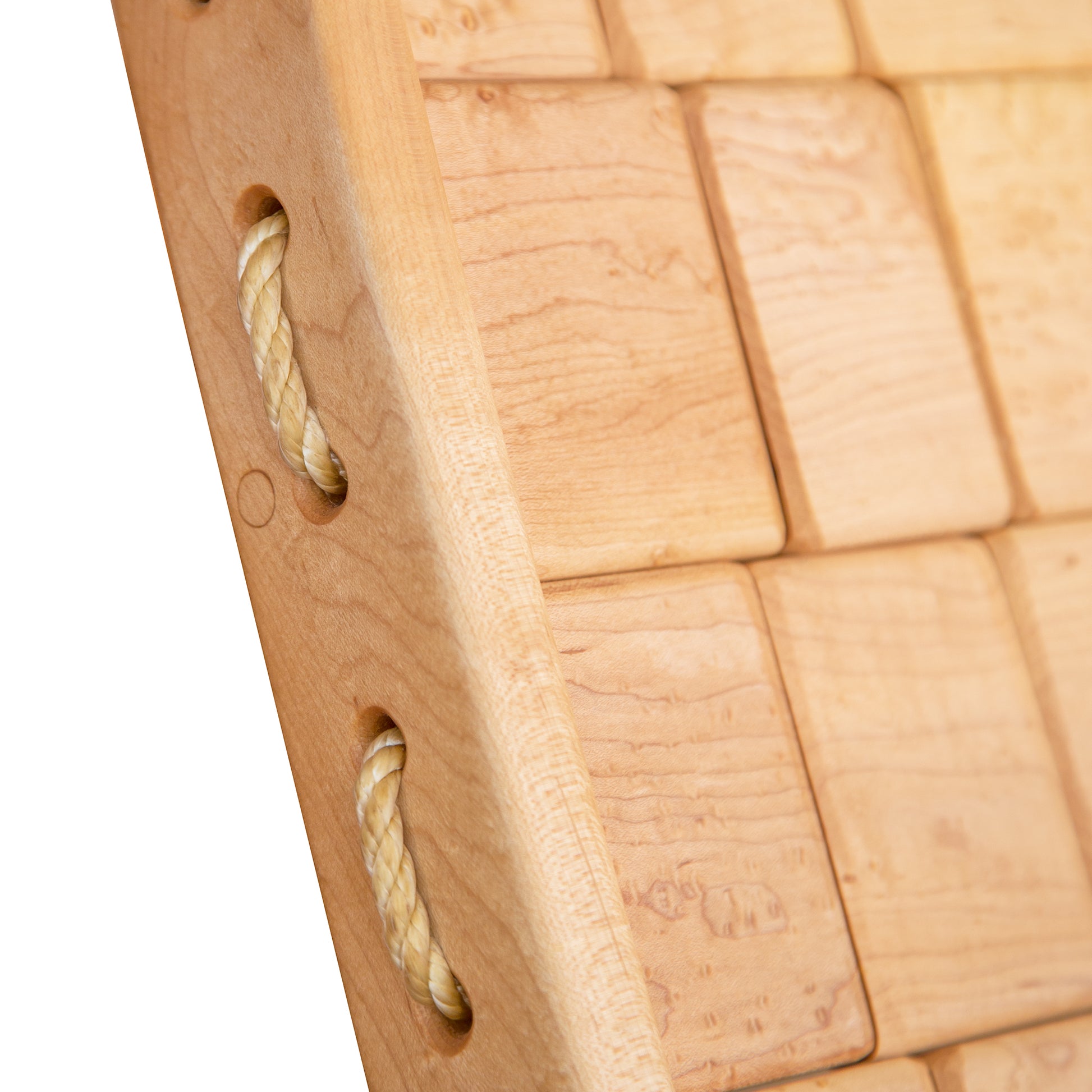 Close-up of a Vermont Folk Rocker Quilted Vermont Birdseye Maple Rocking Chair game board with rope handles inserted into drilled holes on the sides, showing detailed wood grain and texture.