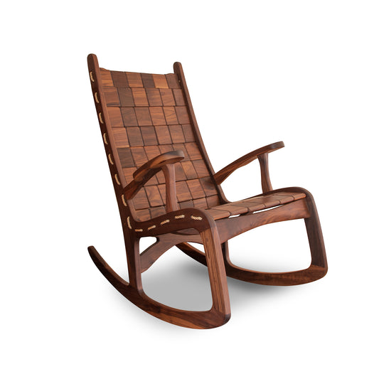 A modern wooden rocking chair made of rich dark brown wood, featuring a sleek, curved design and slatted back and seat in shaker style, isolated on a white background is the Quilted Vermont Walnut Rocking Chair from Vermont Folk Rocker.