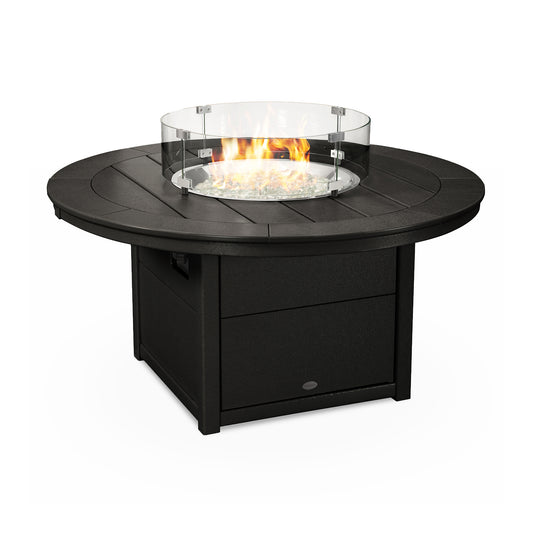 An outdoor POLYWOOD Round 48" Fire Pit Table crafted from POLYWOOD lumber with a black base and a circular glass wind guard, it displays visible flames over a bed of decorative glass pebbles. The surface of the fire pit table adds warmth and ambiance to any outdoor setting.