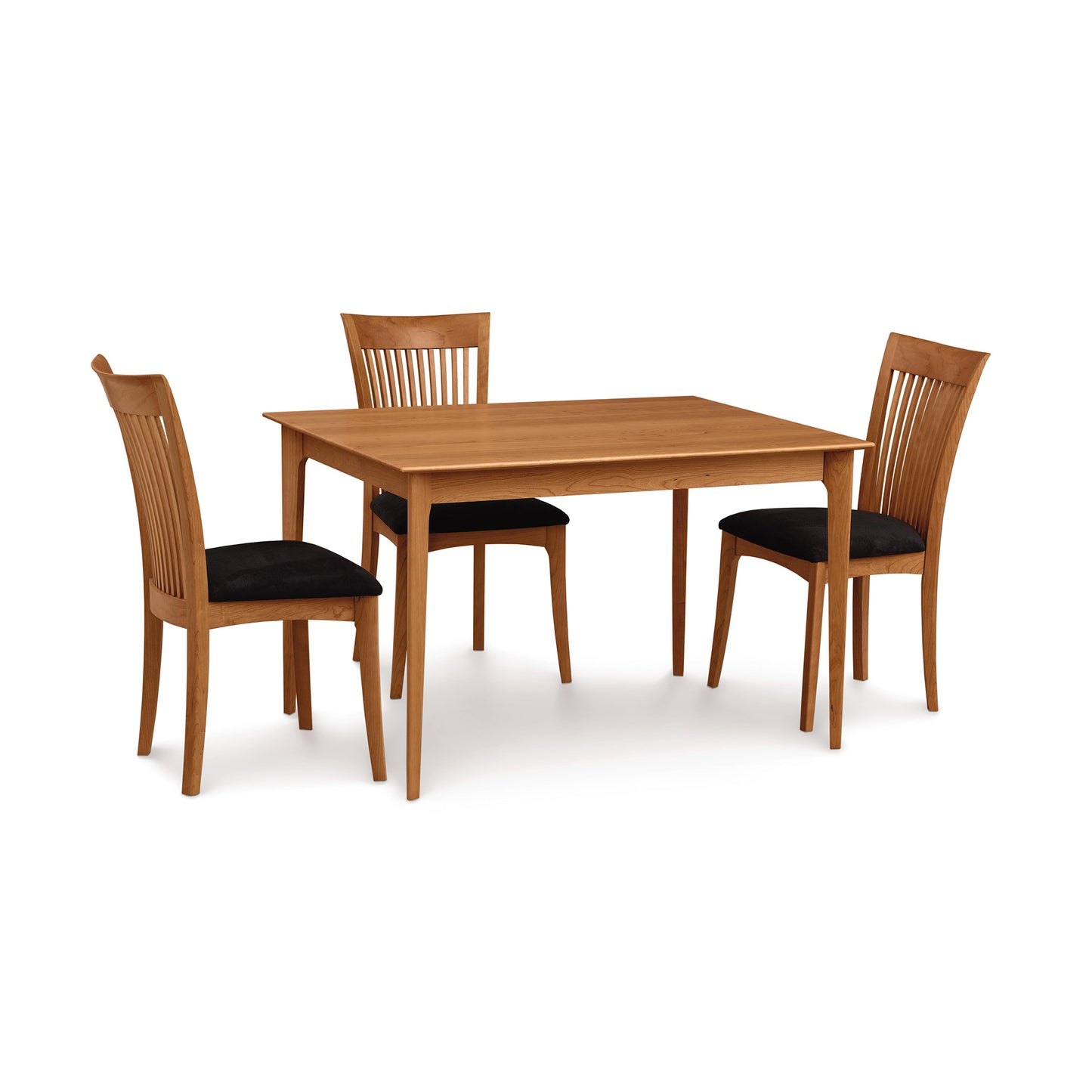 Sarah Shaker solid-top table with tapered legs, paired with three matching dining chairs featuring black cushioned seats by Copeland Furniture.