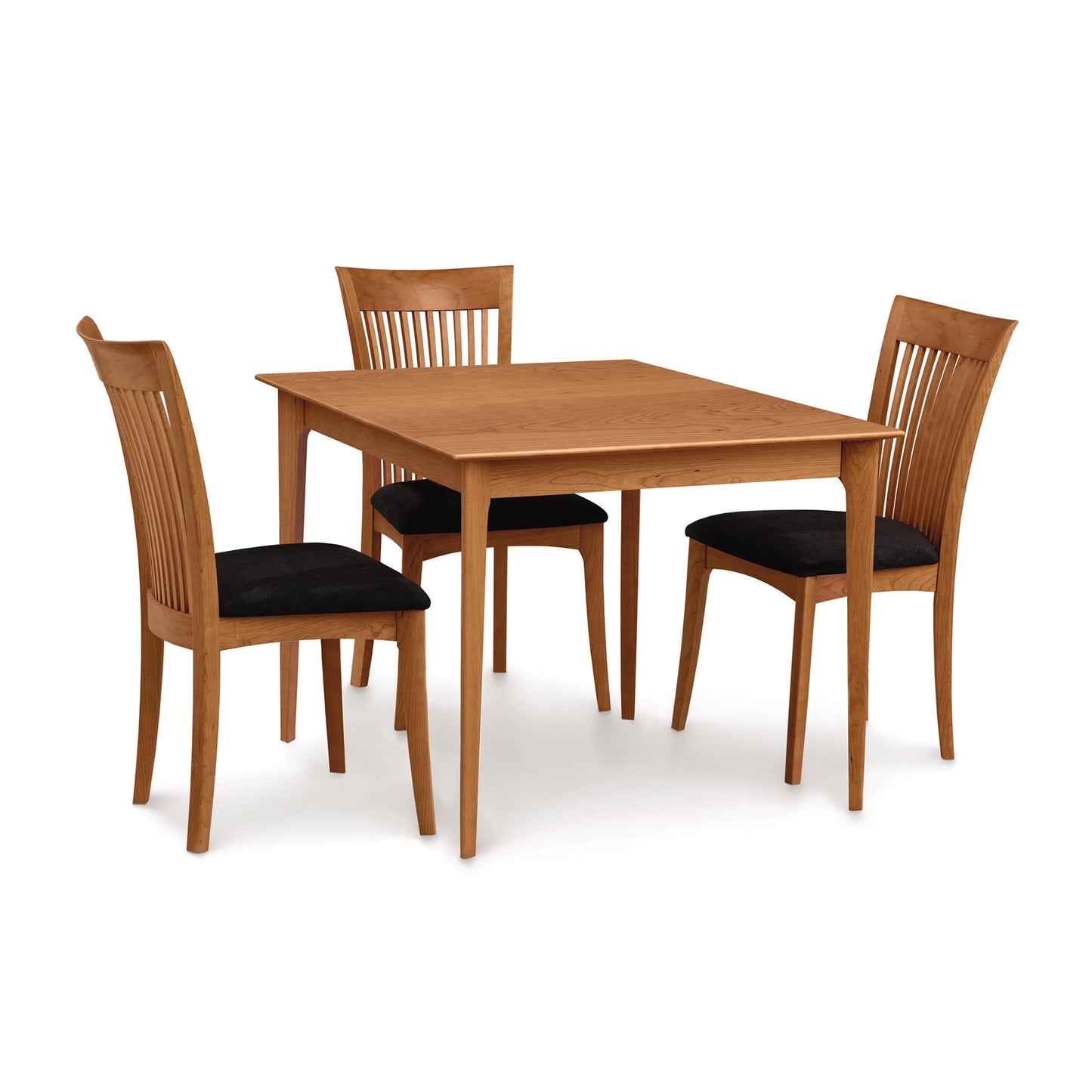 A handmade Copeland Furniture Sarah Shaker Tapered Leg Solid Top Table with four matching chairs, each with a black cushion, isolated on a white background.