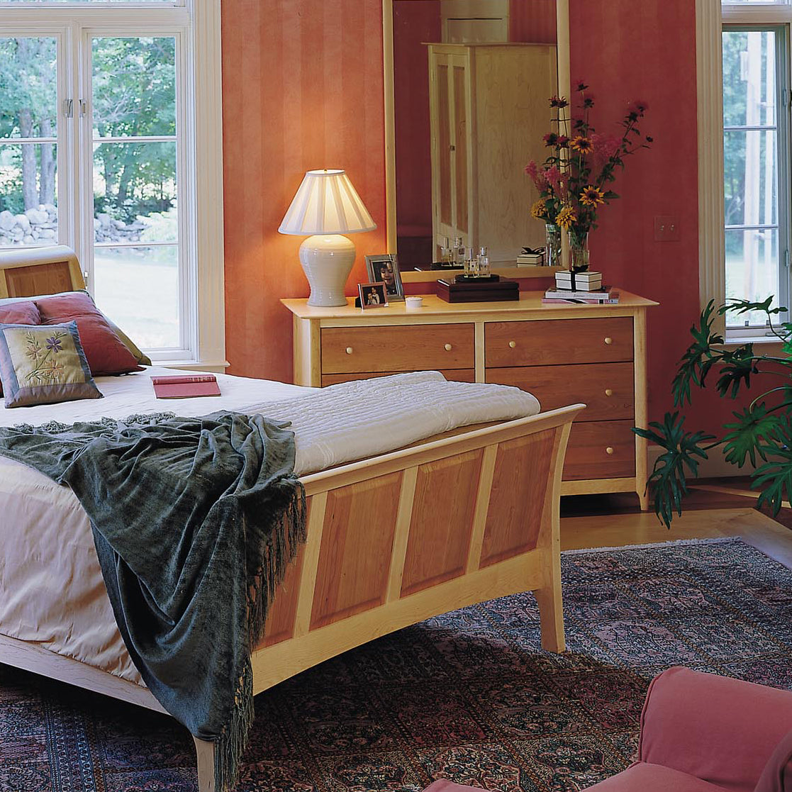 Solid wood bed with white and gray bedding, accompanied by a Copeland Furniture Sarah 6-Drawer Dresser.