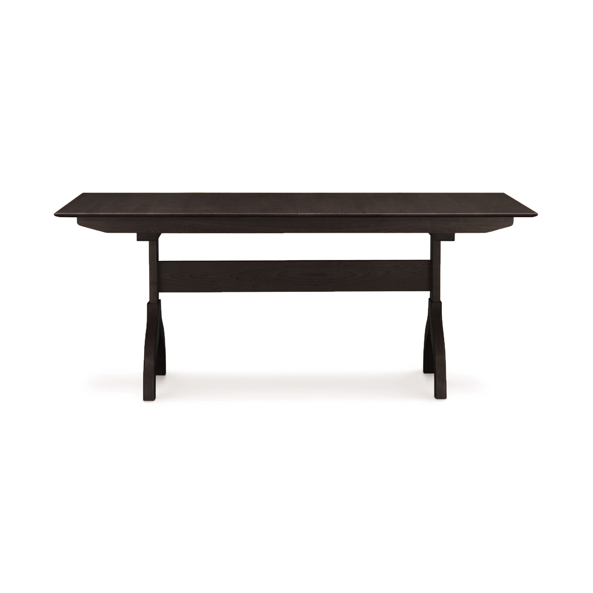 A plain, rectangular wooden Sarah Shaker Trestle Extension Table from the Copeland Furniture Collection, with a dark finish and simple legs, presented against a white background.