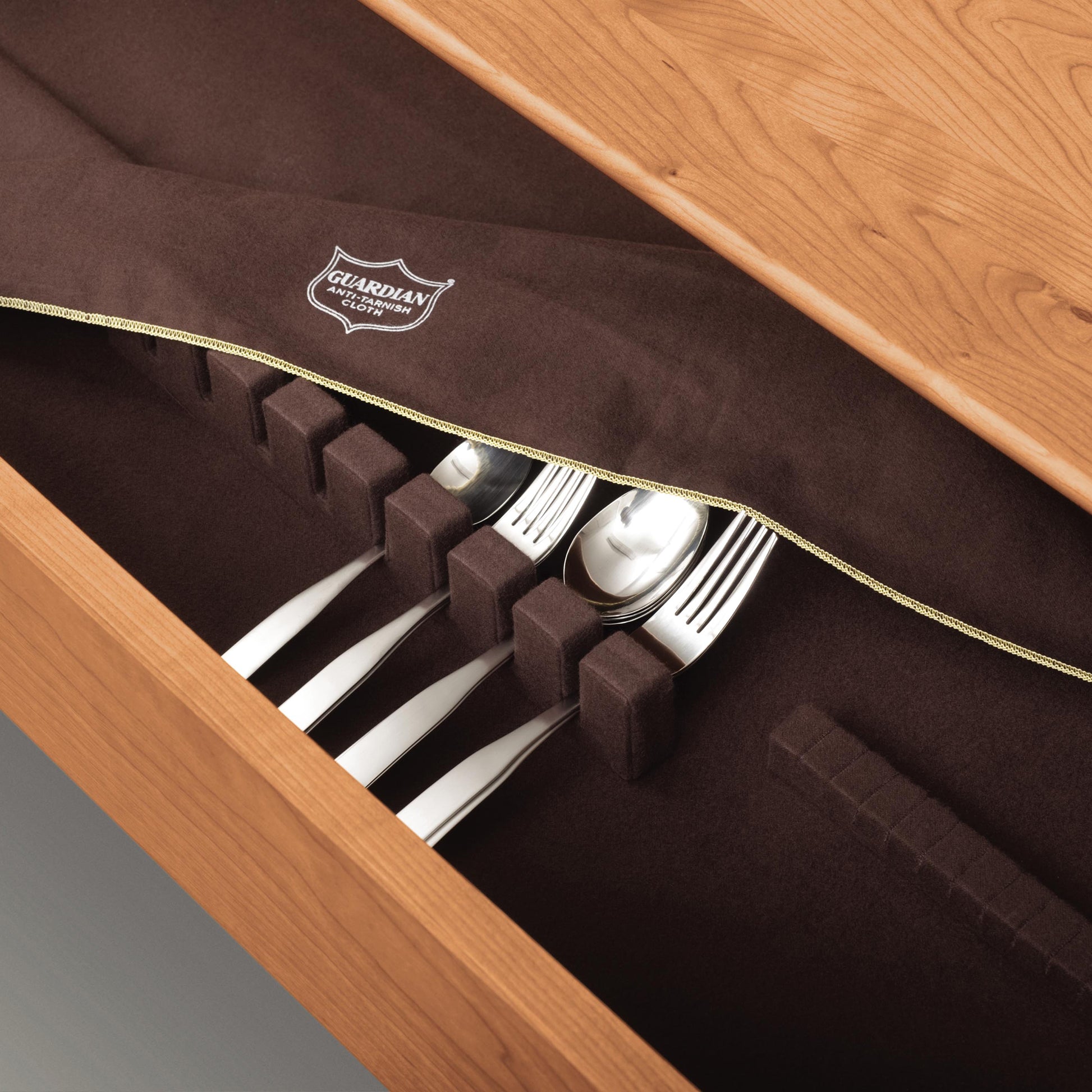 Wooden drawer from the Copeland Furniture Sarah Shaker Collection with a set of cutlery organized neatly in a built-in divider, lined with a dark brown fabric.