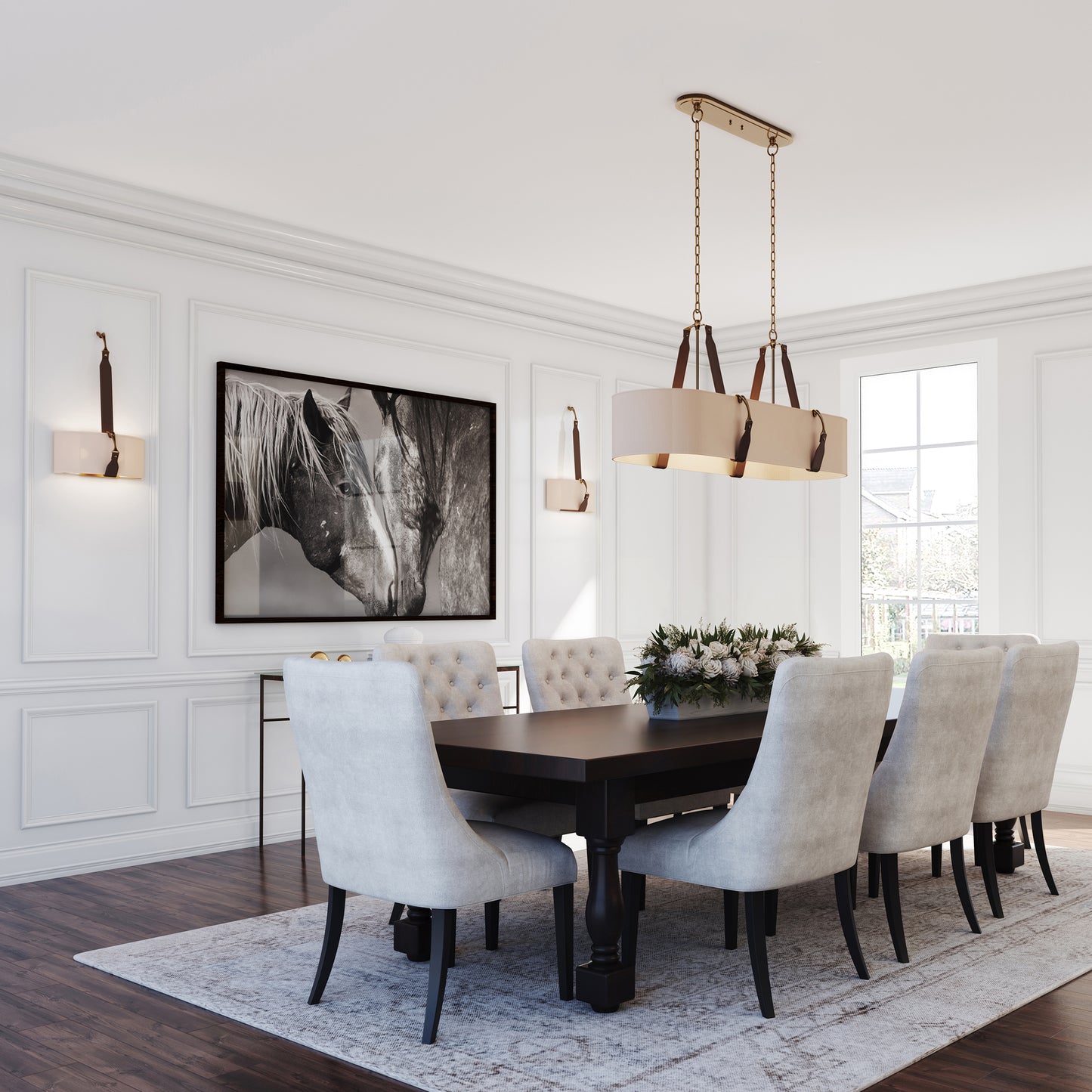 A modern dining room featuring a dark wood table surrounded by light gray upholstered chairs, a Saratoga Oval Pendant from Hubbardton Forge above, and a large black and white photograph on the wall.