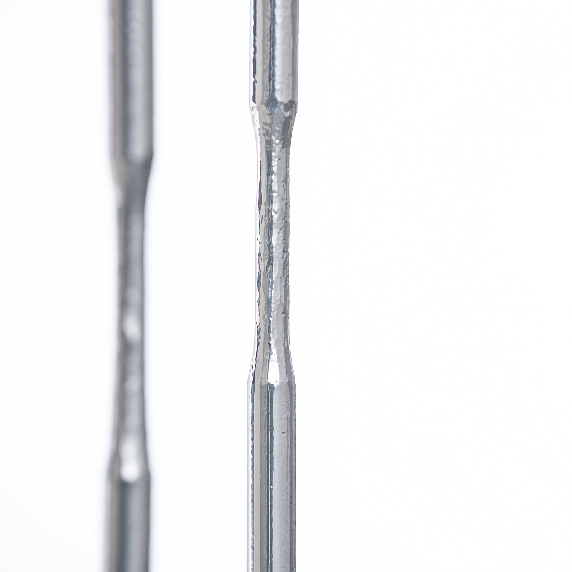 A close up of two metal rods on a white background, resembling a Senza Console Table by Hubbardton Forge.