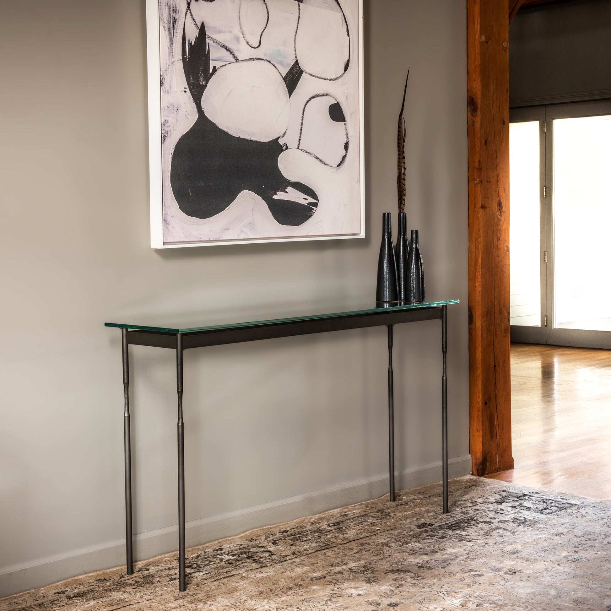 Senza Console Table by Hubbardton Forge with tempered glass top and handcrafted steel legs, highlighting elegant design and quality craftsmanship.