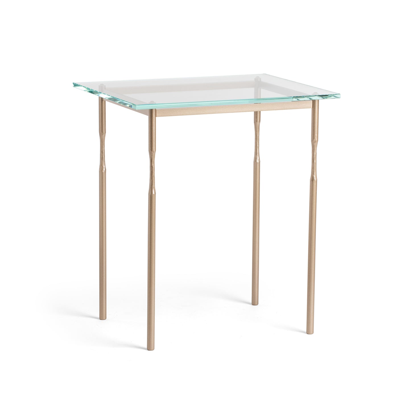 The Hubbardton Forge Senza Side Table is a modern addition to any home. With its fine tailoring and elegant design, this end table features a glass top and gold legs, adding a touch of sophistication.