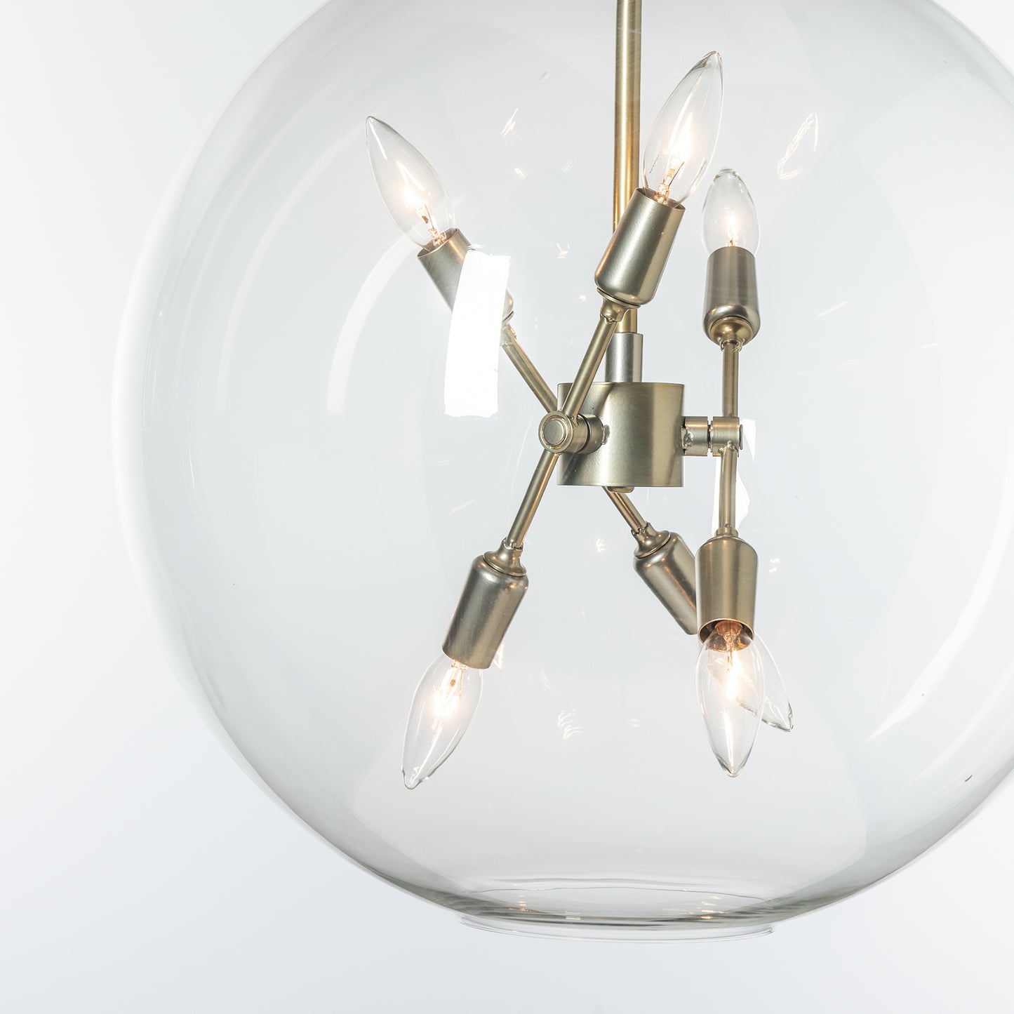 Sfera 6-Light Pendant by Hubbardton Forge featuring a metallic frame, clear glass orb, and six exposed bulbs.