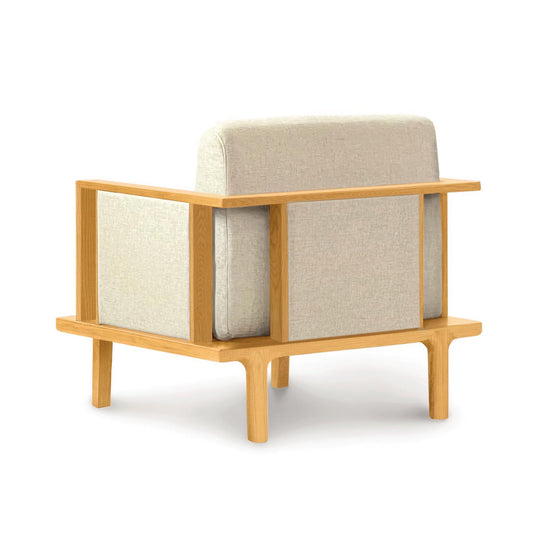 Sierra Upholstered Chair by Copeland with light beige cushion and minimalist wooden frame, back view.