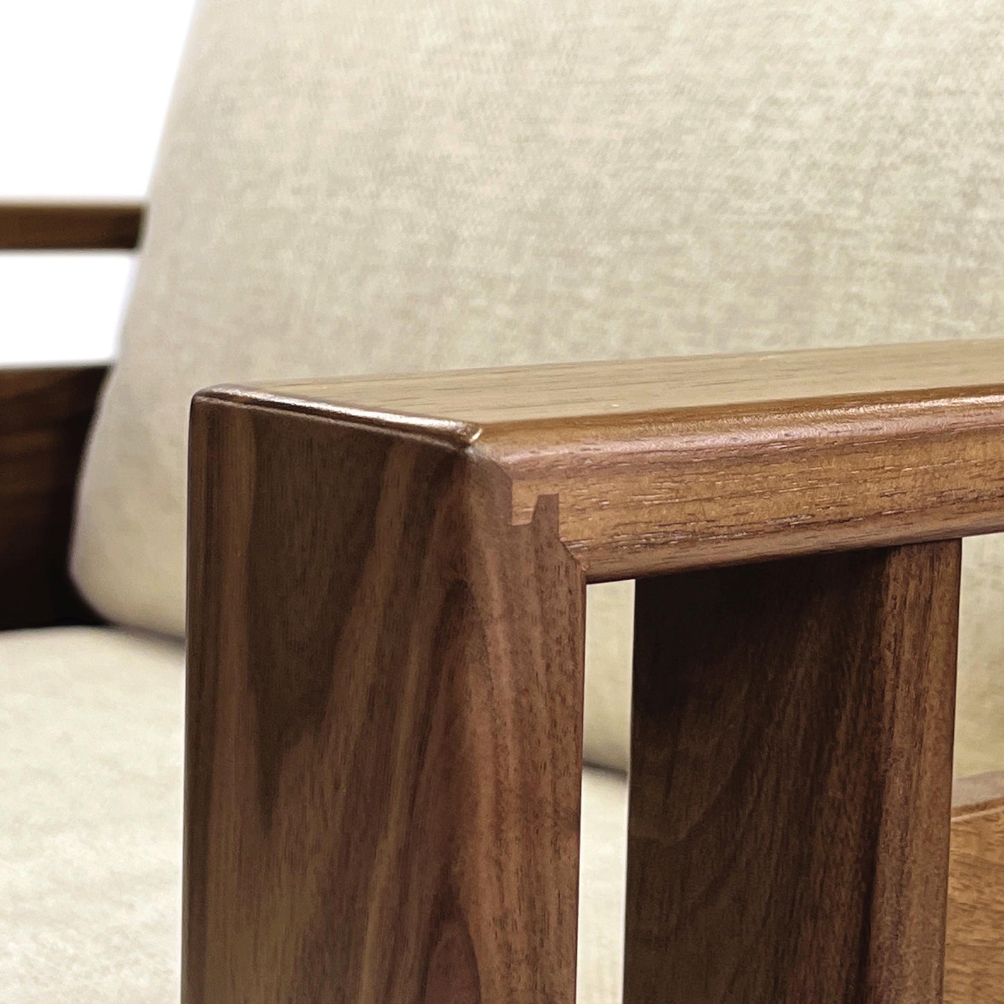 Sierra Upholstered Chair by Copeland Furniture showcasing detailed wooden armrest and corner join, complemented by a beige cushion.
