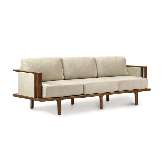 Copeland Furniture's Sierra Walnut Upholstered Sofa with Upholstered Panels, featuring beige cushions and a contemporary design, stands out against a white background.