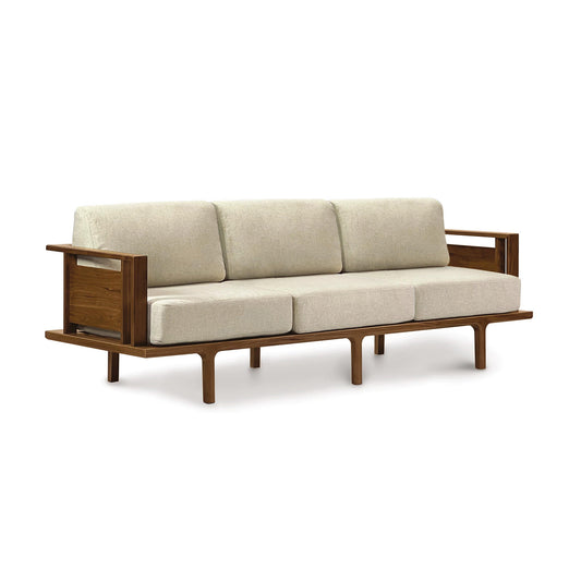 A Copeland Furniture's Sierra Walnut Upholstered Sofa, featuring contemporary design with beige cushions set against a white background.