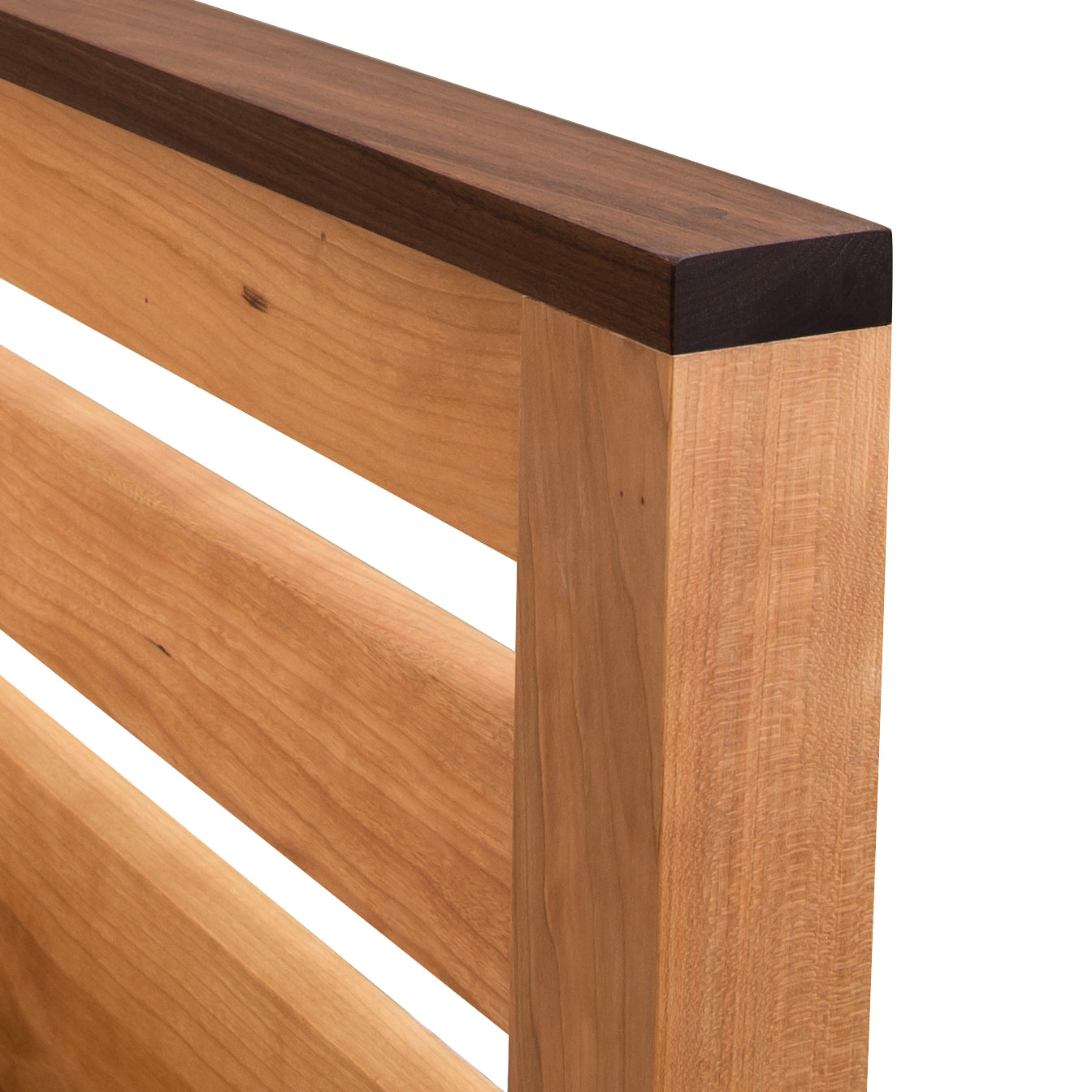 A close-up of a solid Cherry, eco-friendly Vermont Furniture Designs Skyline Panel Bed frame corner showcasing the joinery and wood grain details.