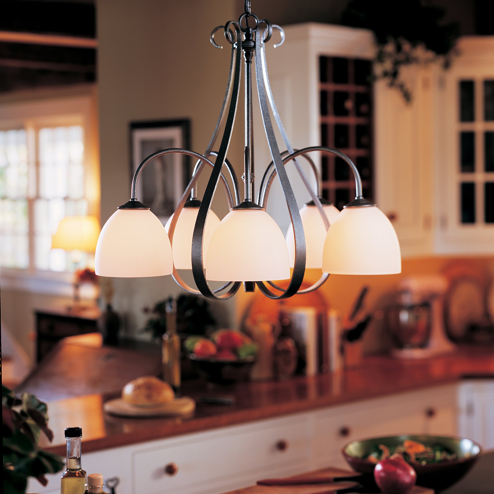 The Hubbardton Forge Sweeping Taper 5-Arm Chandelier brightens up the dining area in the kitchen.