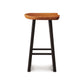A Modern Farmhouse Tractor Counter Stool by Copeland Furniture with a tractor seat and black legs stands isolated against a white background.