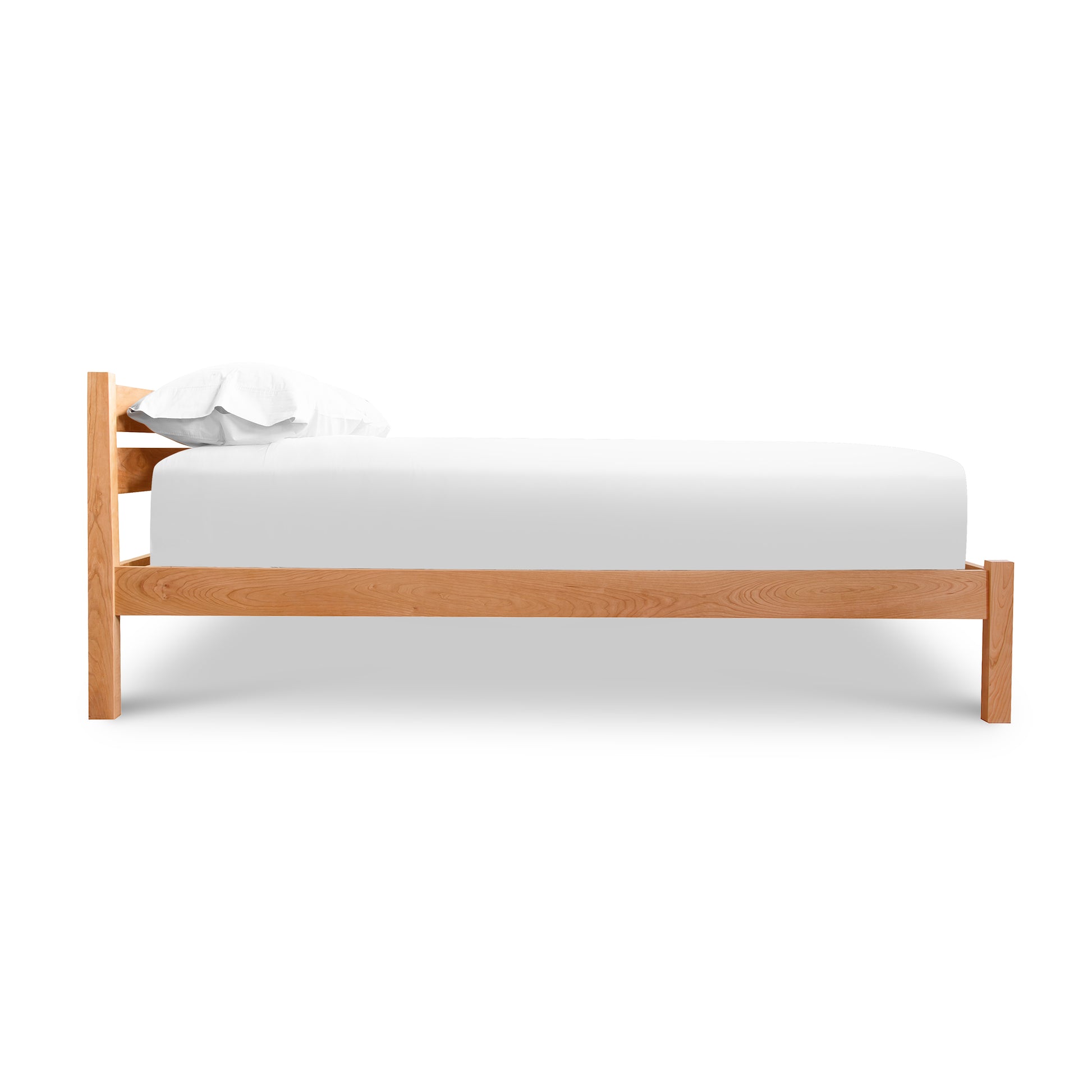 Eco-friendly hardwood Vergennes Platform Bed by Vermont Furniture Designs with white mattress and pillows viewed from the side.
