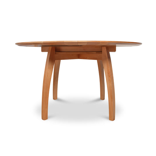 Vermont Modern Round Pedestal Extension Table, crafted from solid wood with a sleek surface and elegantly curved legs by Lyndon Furniture.