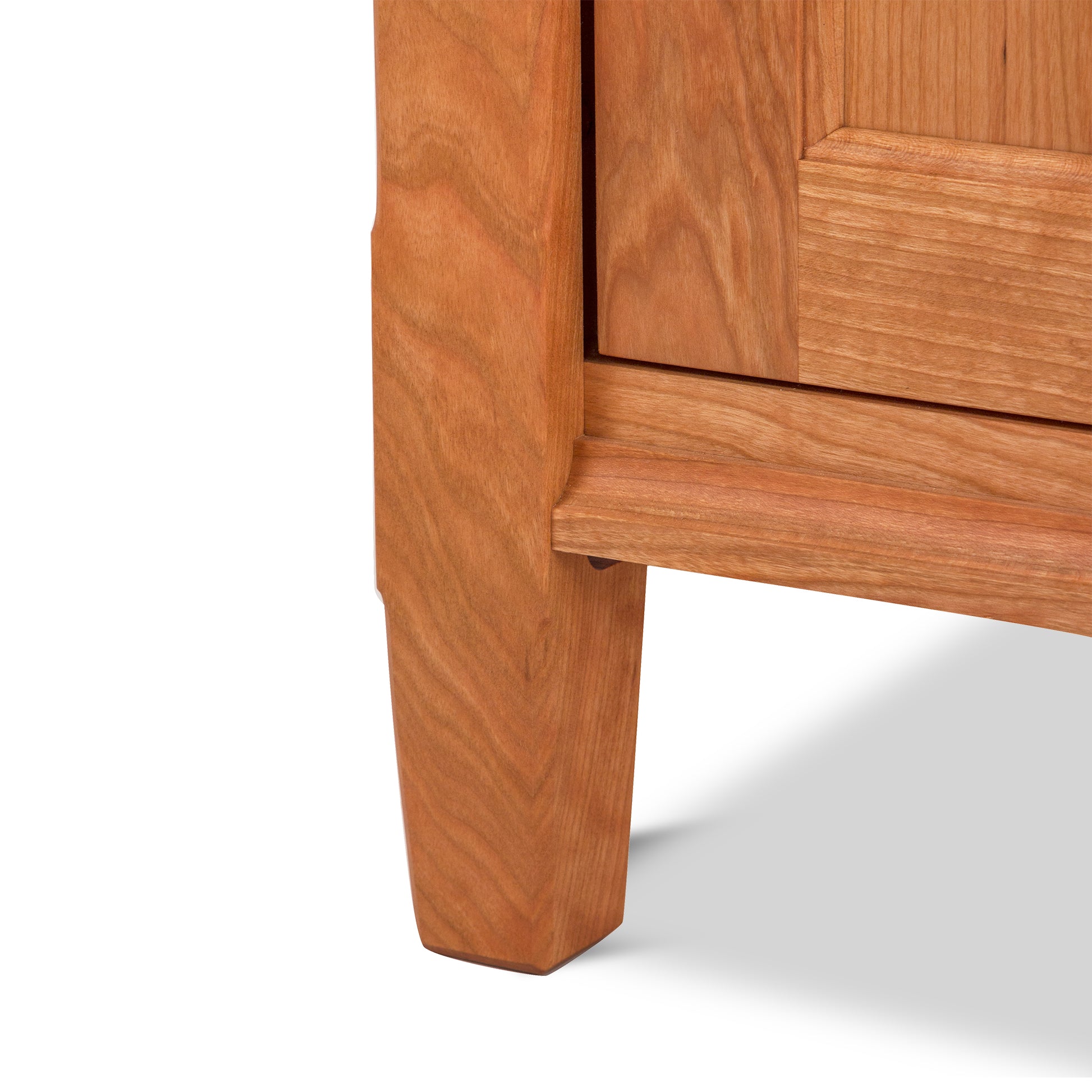 Close-up of a wooden drawer and leg of a Maple Corner Woodworks Vermont Shaker 1-Drawer Nightstand with Door, showing detailed wood grain and construction, isolated on a white background.