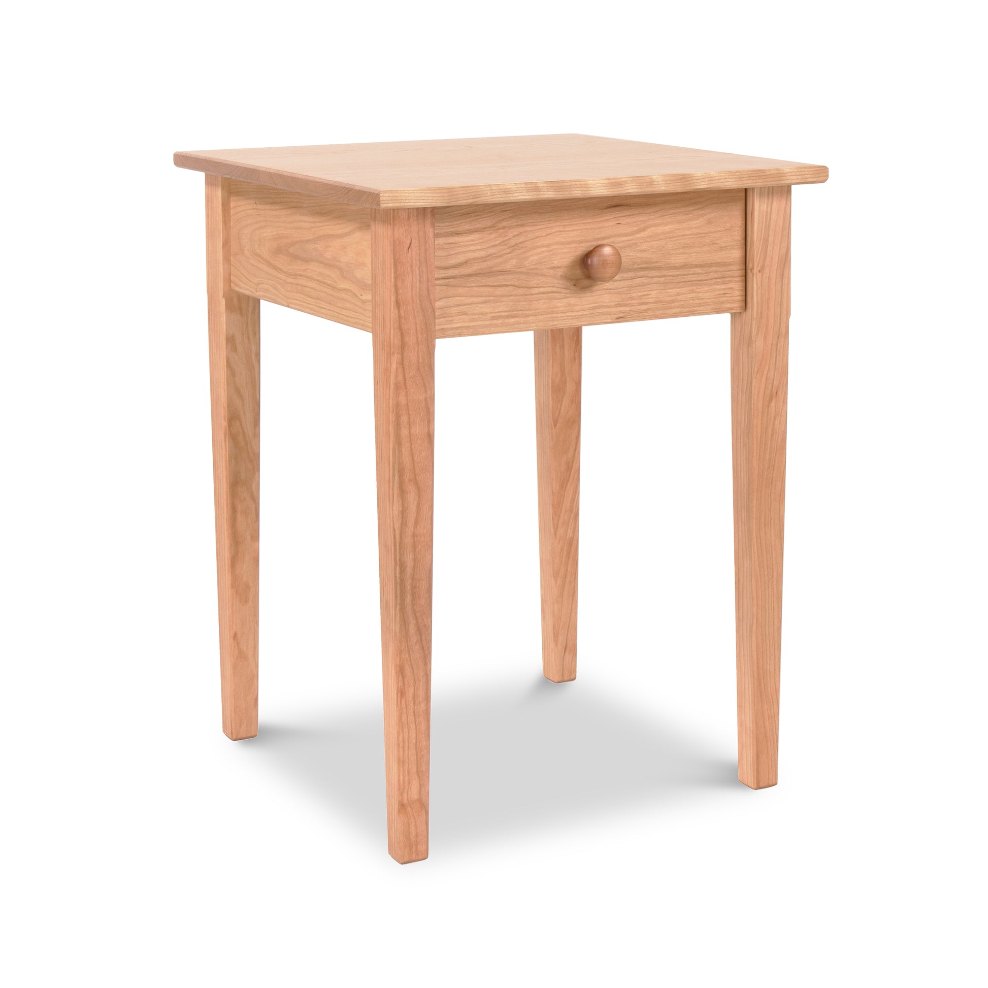 A Vermont Shaker Bedside Table from Maple Corner Woodworks, with one drawer and round knob, featuring slim, straight legs and a smooth top, isolated on a white background.