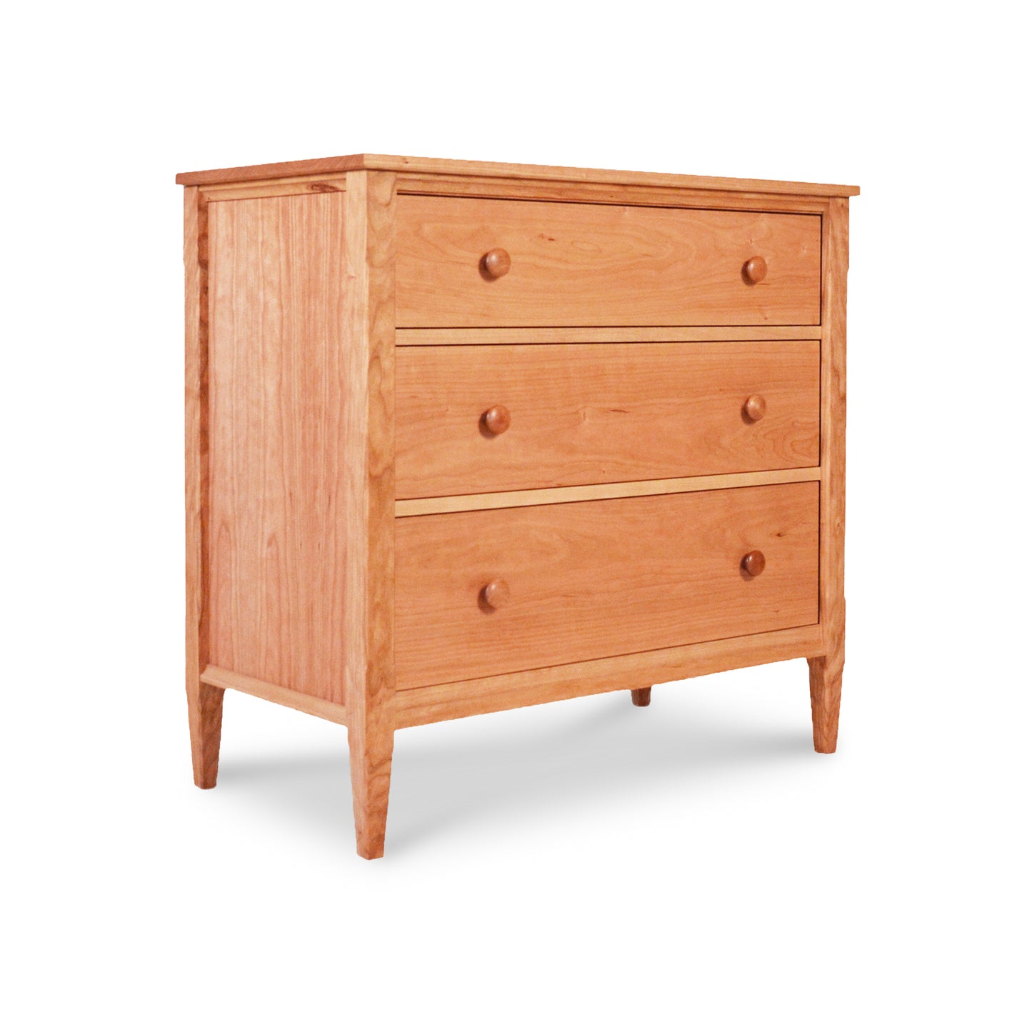 A Vermont Shaker 3-Drawer Chest from Maple Corner Woodworks, with round knobs and elevated legs, isolated on a white background. The wood has a natural, light finish.
