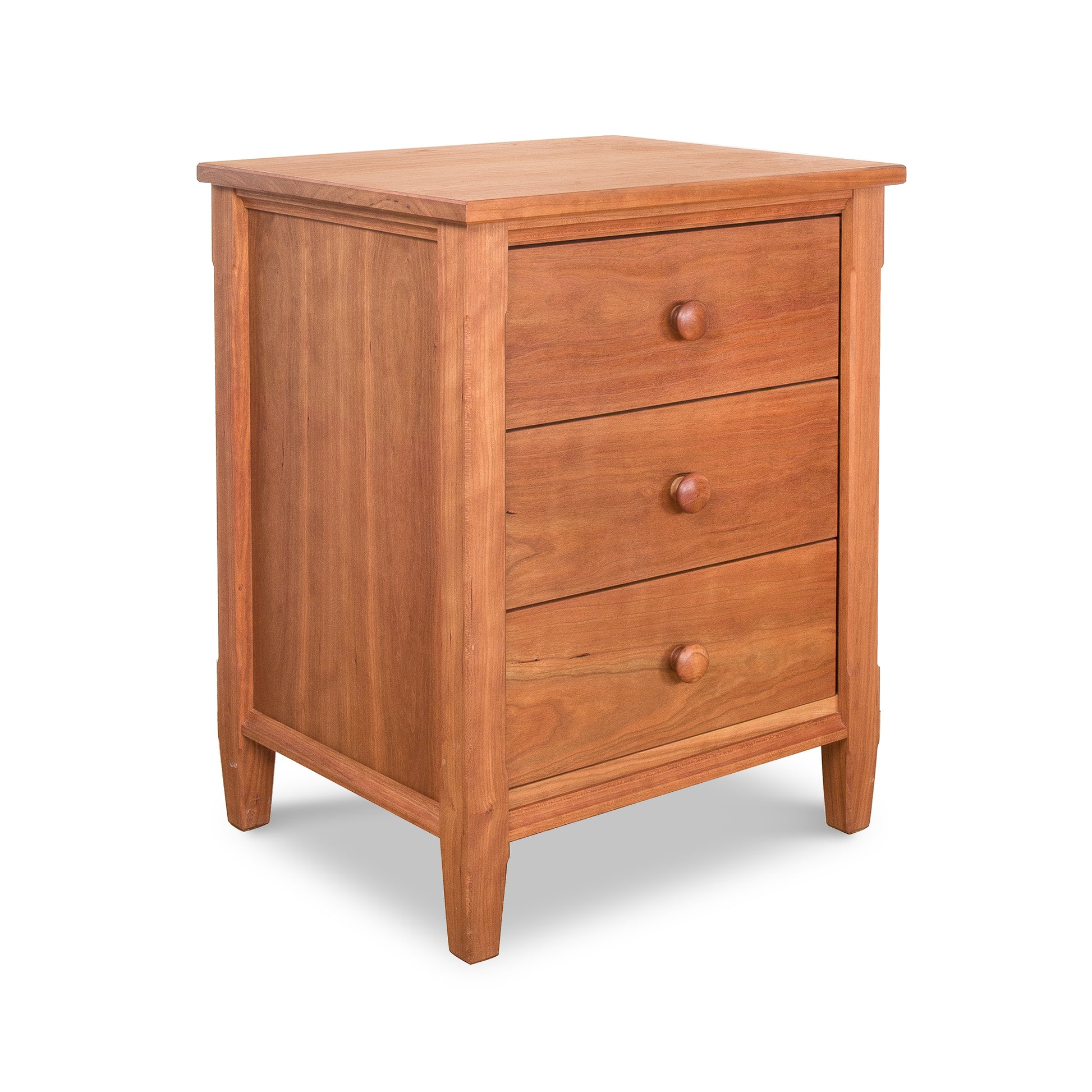 A wooden three-drawer Vermont Shaker Nightstand with round knobs, made from sustainably harvested natural hardwoods, isolated on a white background.