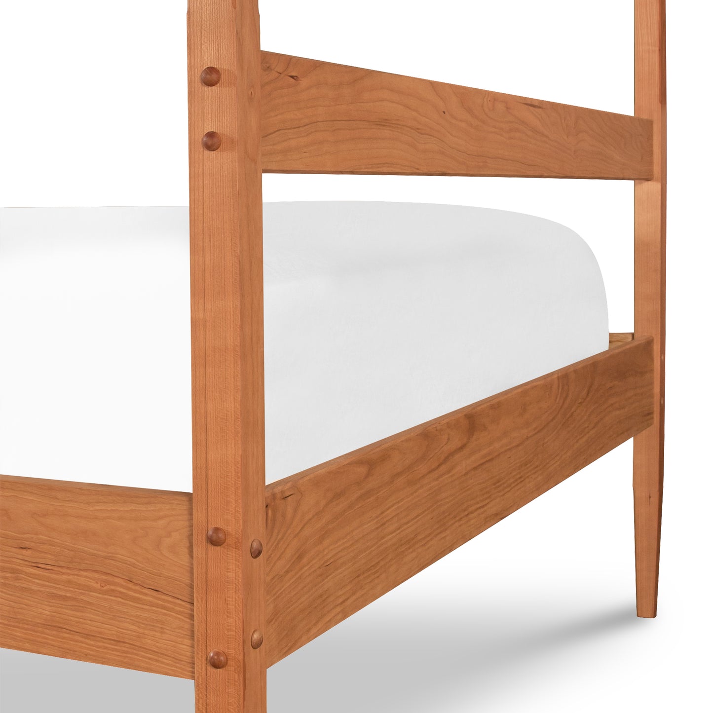 A close-up view of a wooden Vermont Shaker Four Poster Bed frame by Maple Corner Woodworks highlighting the clean, simple design and natural wood grain, with a white mattress on the lower bunk.