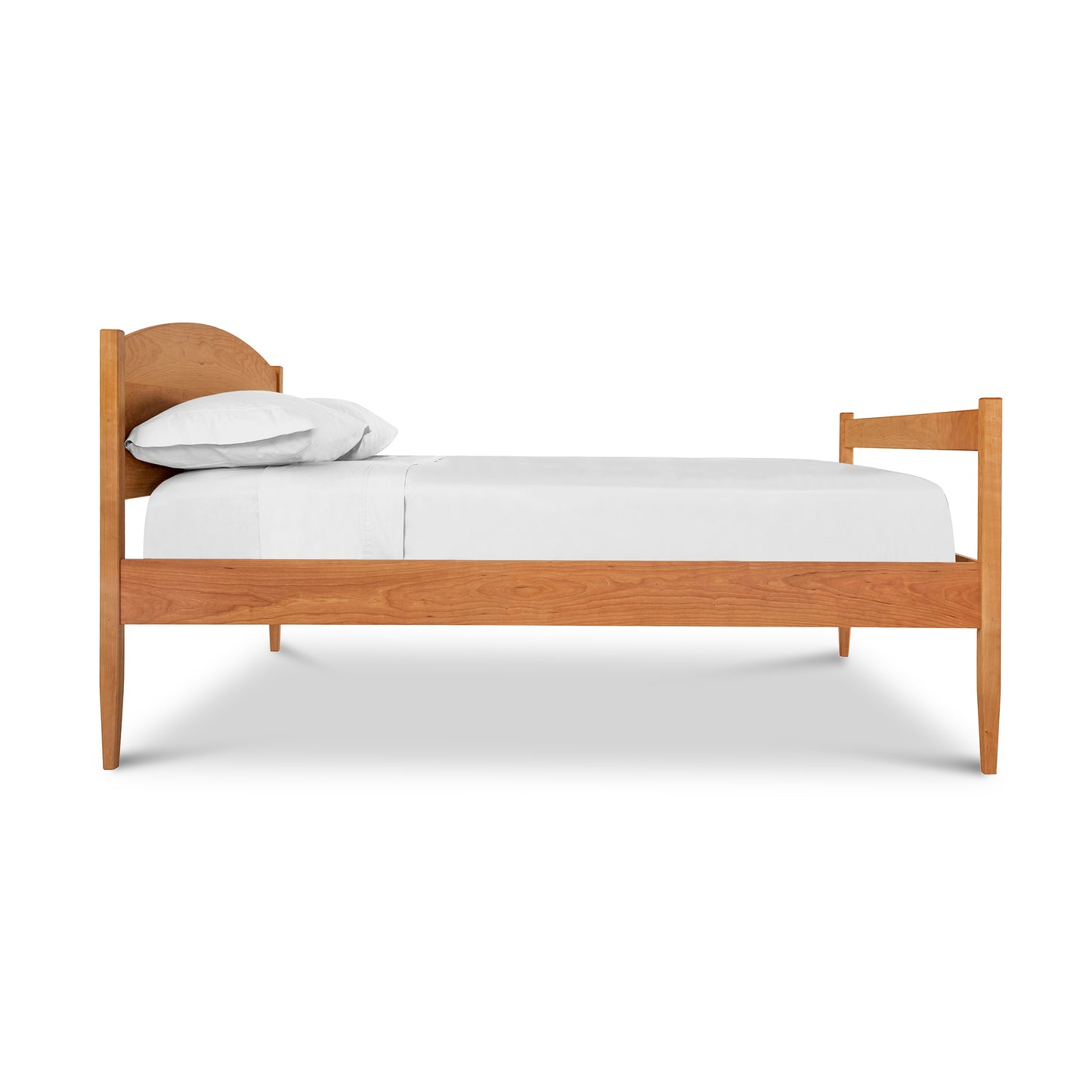 A simple Maple Corner Woodworks Vermont Shaker Bed frame with a curved headboard and a white mattress and pillow set against a plain white background.