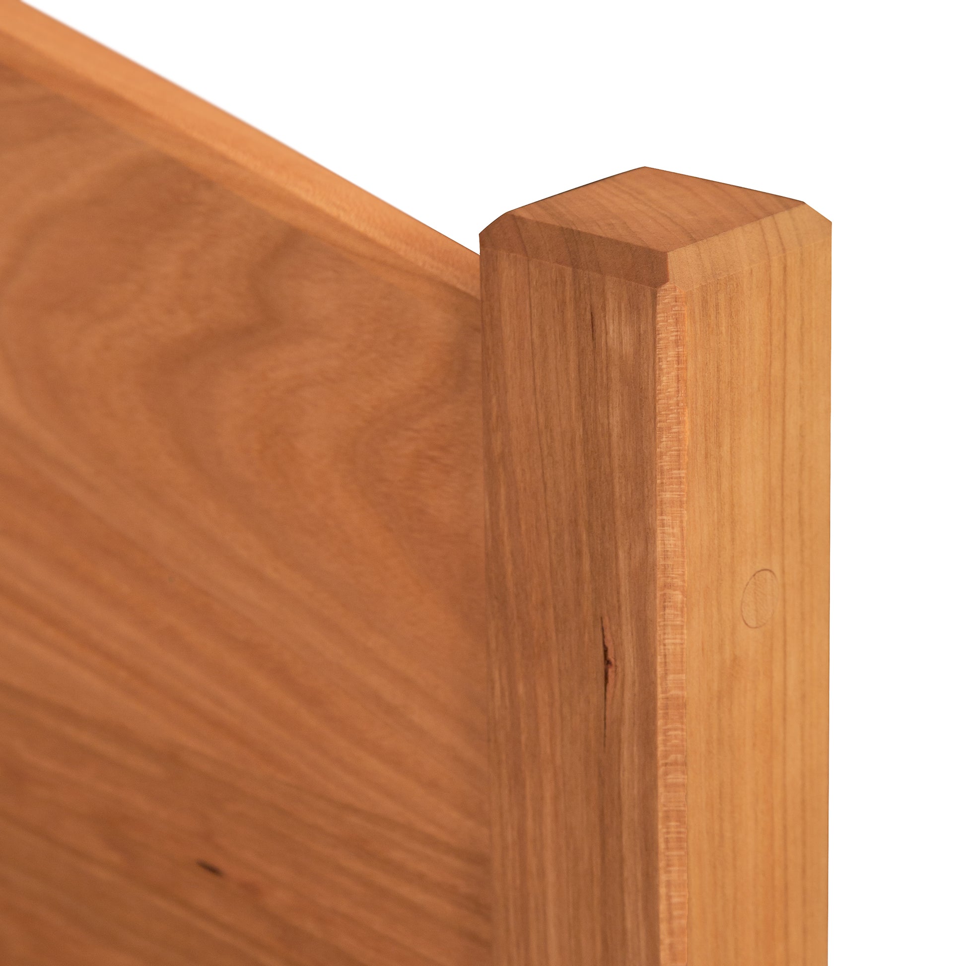 Close-up of the Vermont Shaker Bed frame by Maple Corner Woodworks, highlighting the detailed wood grain and sleek finish on the corner post and panel.