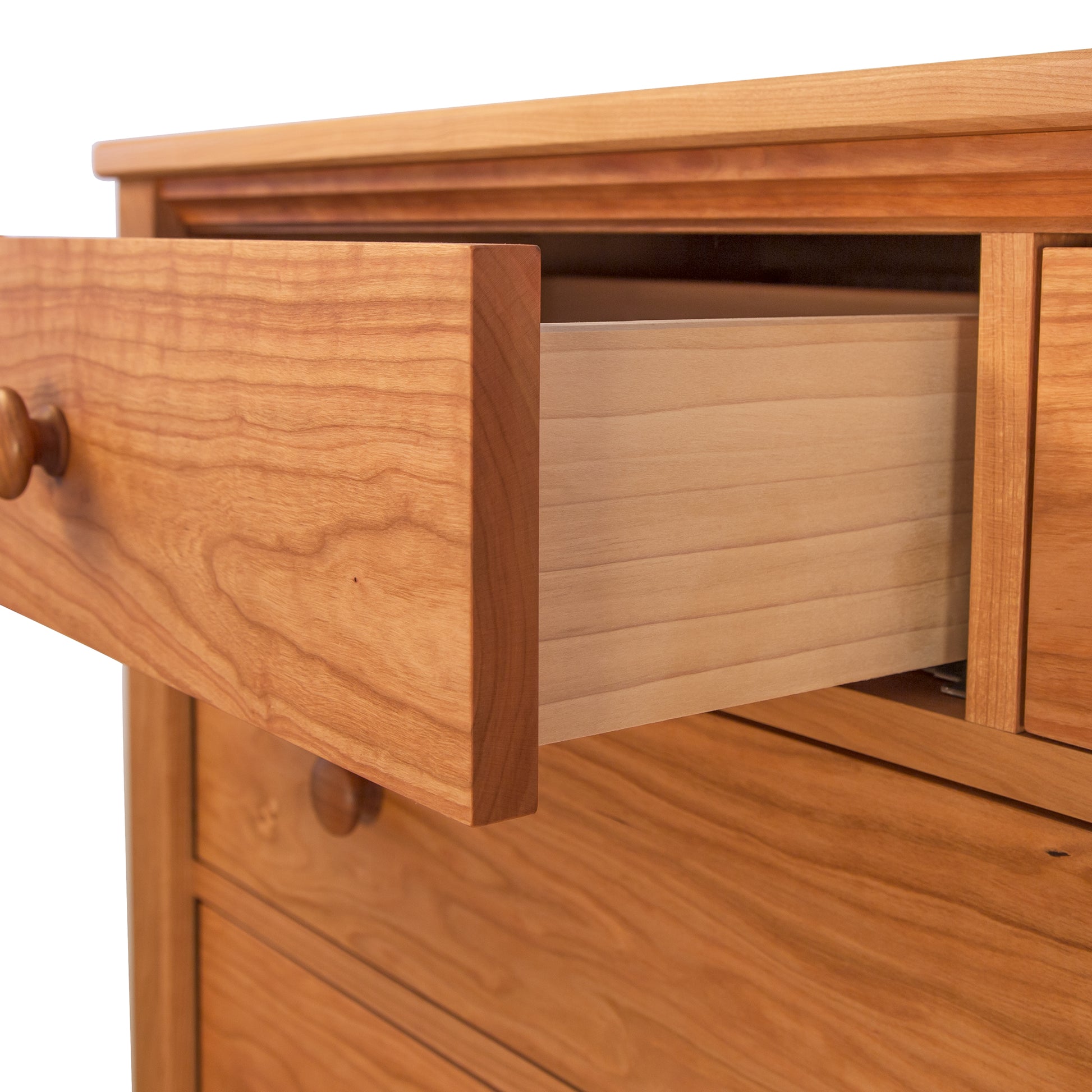 An open drawer of a Vermont Shaker Extra Wide Chest from Maple Corner Woodworks, highlighting the grain and craftsmanship. The drawer is partially extended, showcasing its construction and smooth interior.