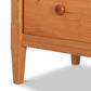 Close-up of a Vermont Shaker Extra Wide Chest by Maple Corner Woodworks featuring a single drawer with a round knob and tapered legs, highlighting the smooth, natural cherry wood grain.