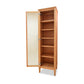 A solid wood bookcase resembling a Maple Corner Woodworks Vermont Shaker Narrow Bookcase with Mirror, with an open door, revealing four empty shelves, isolated on a white background.