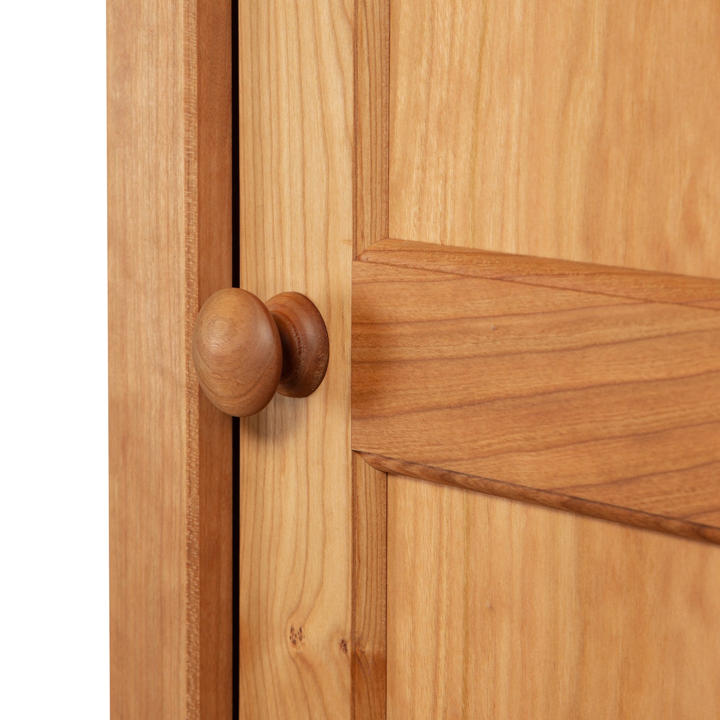 Close-up of a natural cherry hardwood door with a round knob, showcasing craftsmanship similar to the Vermont Shaker bookcase by Maple Corner Woodworks.