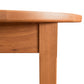 Close-up of a Vermont Shaker Oval Extension Dining Table from Maple Corner Woodworks showing the smooth, rounded edge and grain details, isolated on a white background.