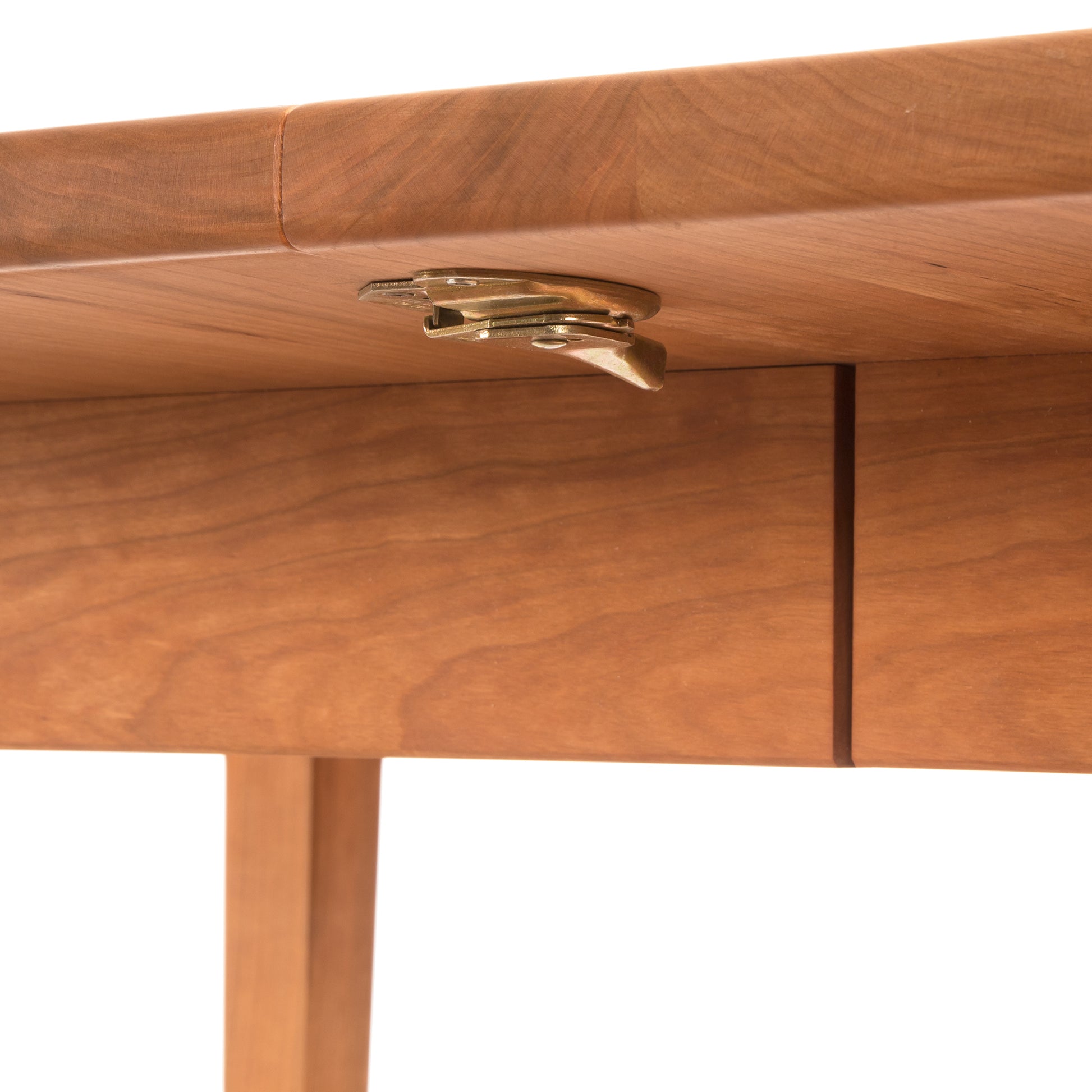 Close-up of a Maple Corner Woodworks Vermont Shaker Oval Extension Dining Table with an open drawer, showcasing the metallic drawer handle attached beneath the tabletop. The wood has a warm, reddish-brown hue with a smooth finish.