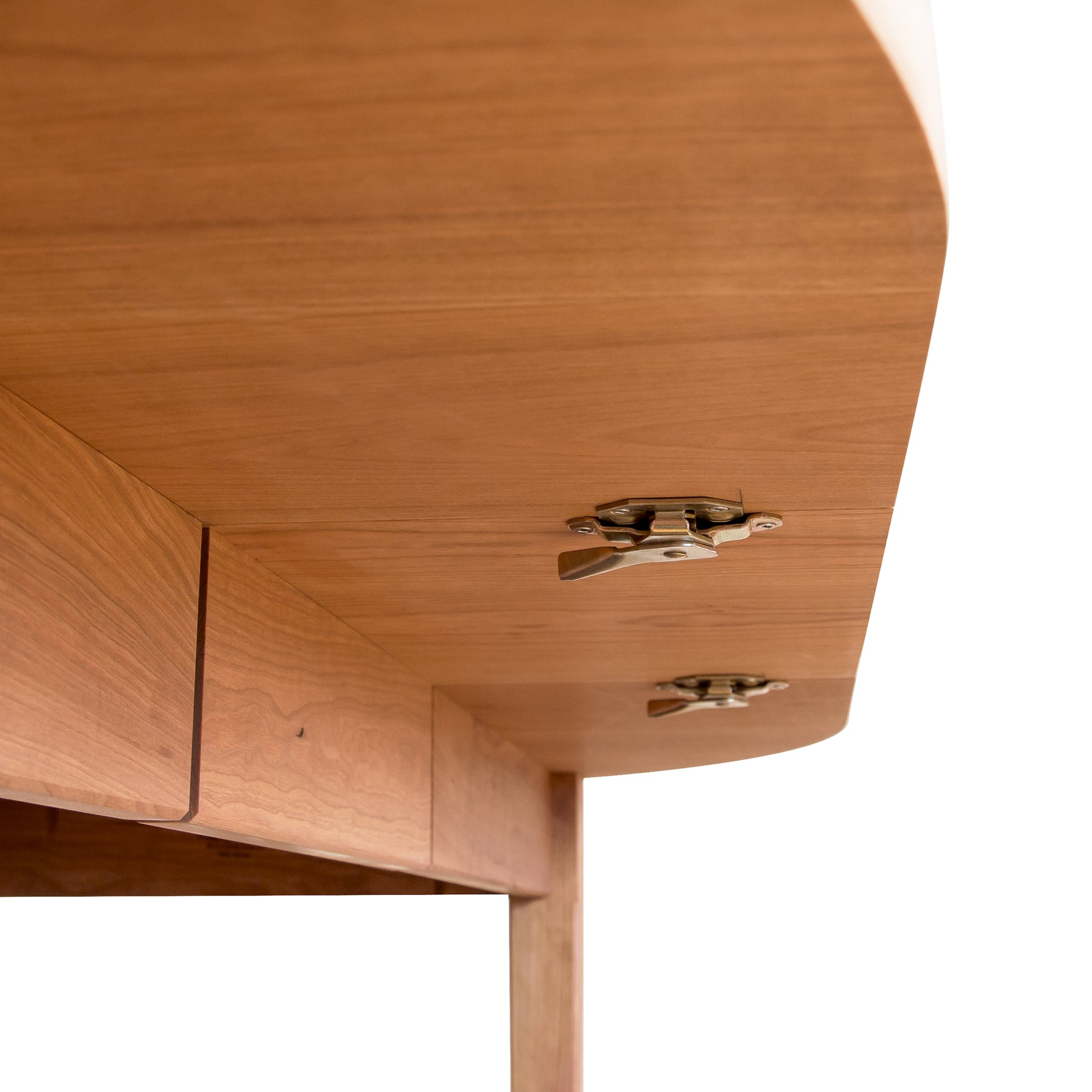 Close-up of a Vermont Shaker Oval Extension Dining Table drawer, crafted from sustainably harvested wood by Maple Corner Woodworks, showing metal hinges partially open, with a clean, minimalist design. The background is a soft beige, focusing on the craftsmanship.