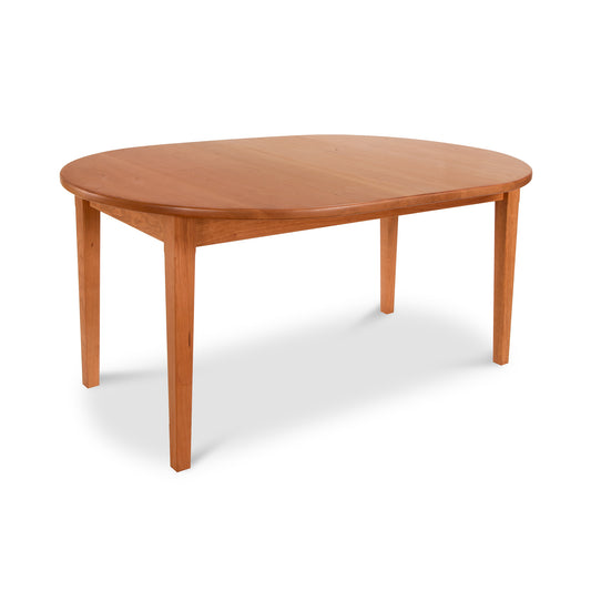 A simple oval Maple Corner Woodworks Vermont Shaker dining table with four legs, isolated on a white background. The table is made of light brown solid wood with a smooth finish.