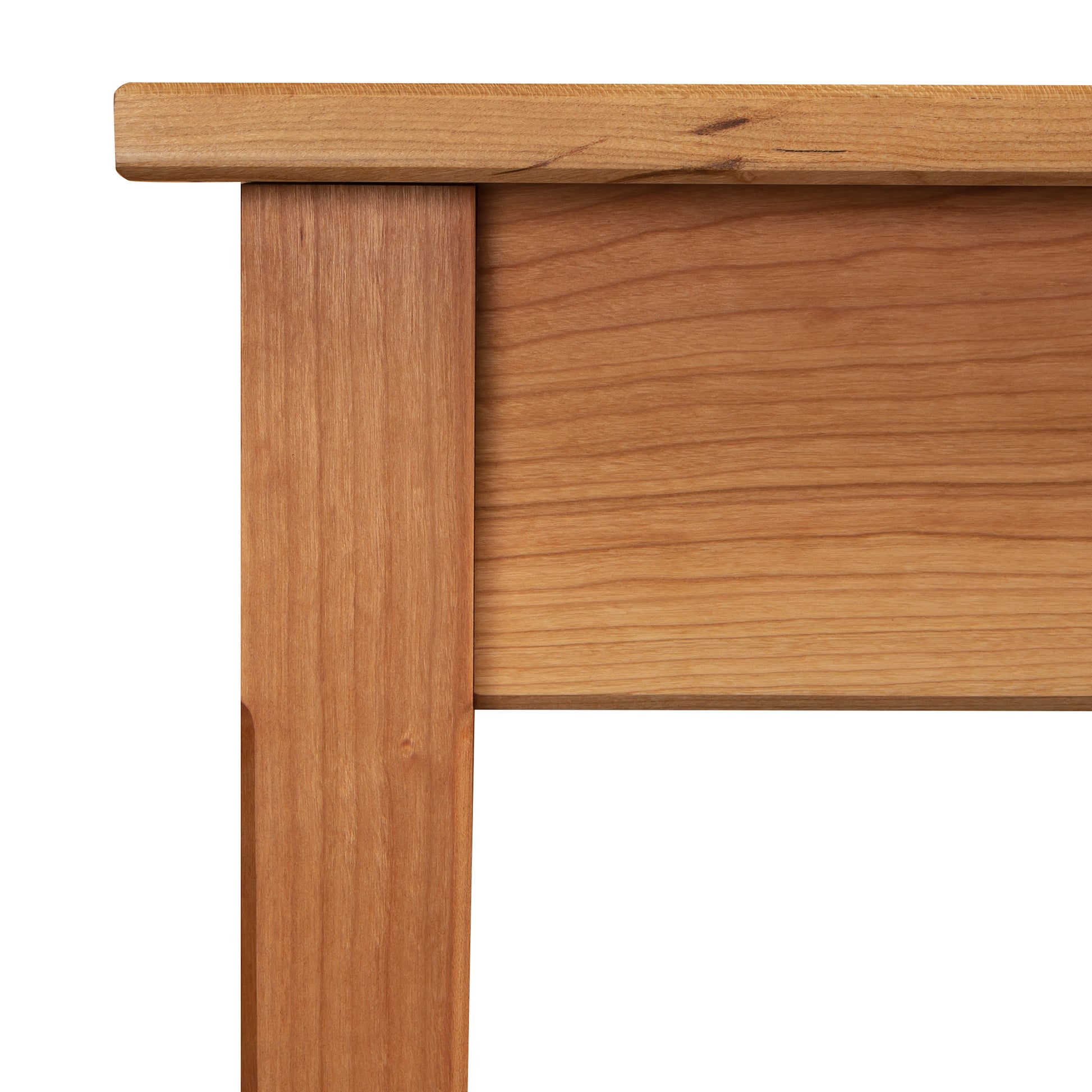 A Maple Corner Woodworks Vermont Shaker Writing Desk corner with a solid wood construction leg and a flat surface, showcasing the wood grain and joints, on a white background.