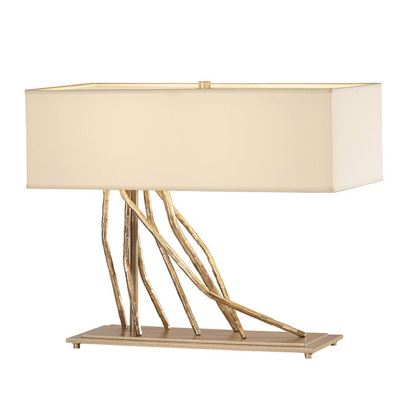 Brindille Table Lamp by Hubbardton Forge featuring a cream shade, dark smoke finish, and gold branch-inspired base.