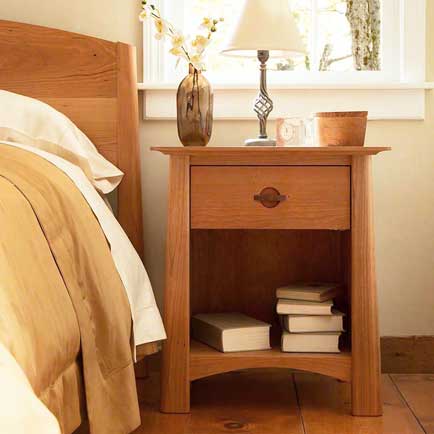 A wooden nightstand with a lamp and books on it.