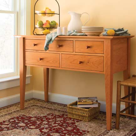 A table with drawers and a rug in a room.