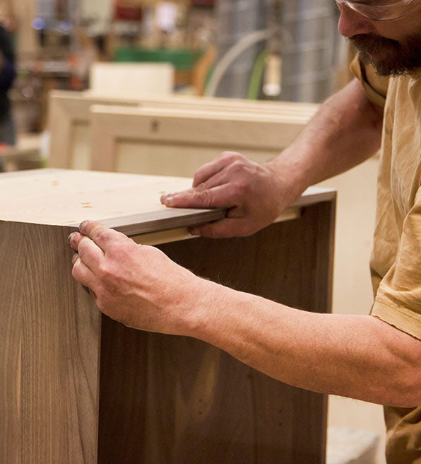 A man is working on a piece of wood in a factory.