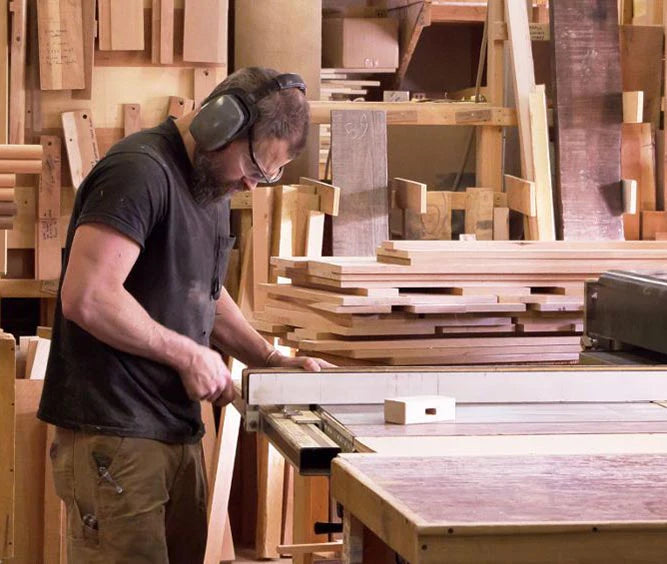 A craftsman using a table saw to cut wood for high-quality furniture creation.