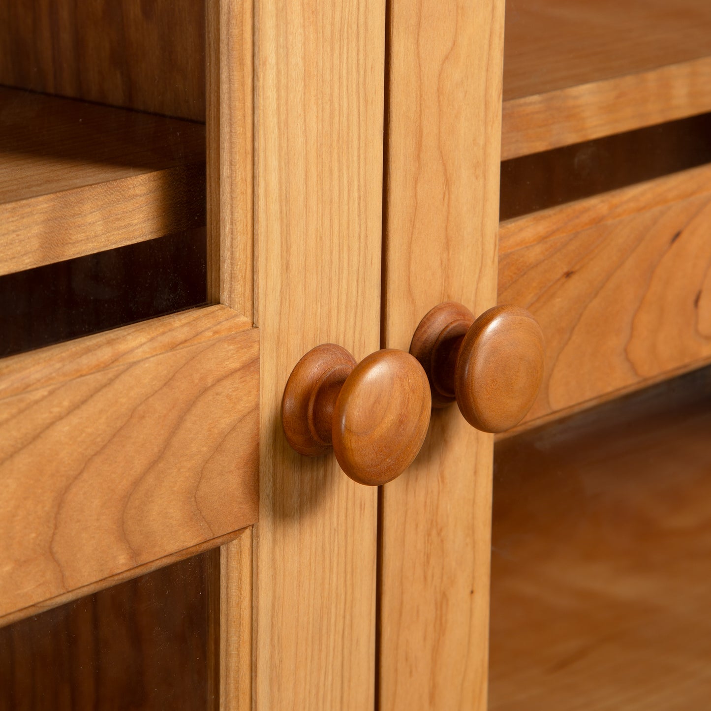 Maple Corner Woodworks Vermont Shaker bookcase with glass doors, featuring two round wooden knobs on the cabinet front.