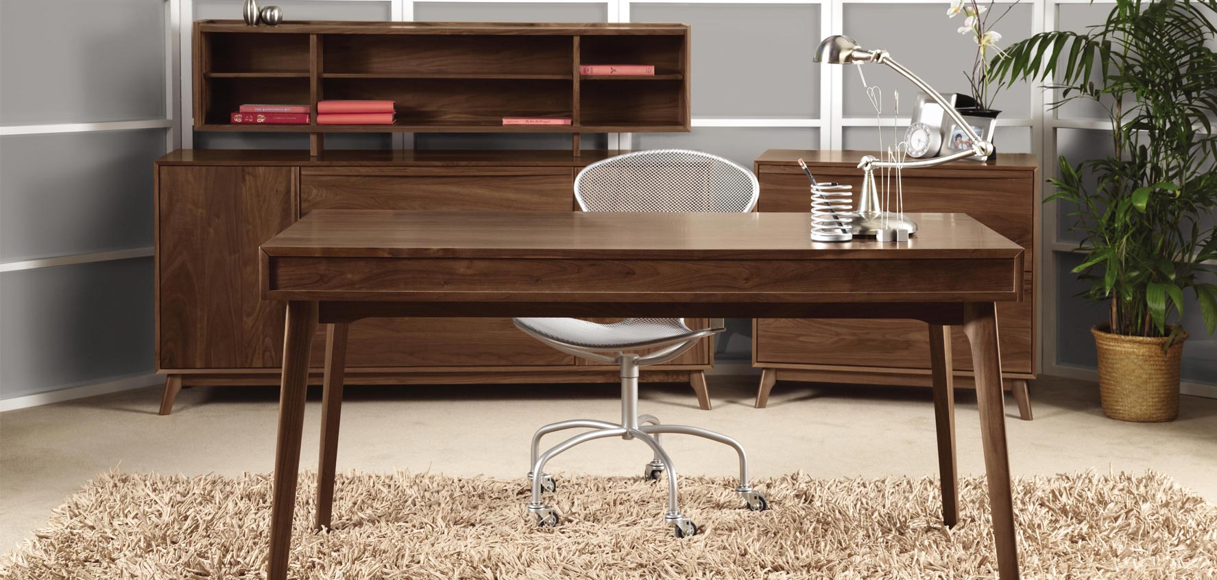 A modern home office with a desk, chair and bookshelf.