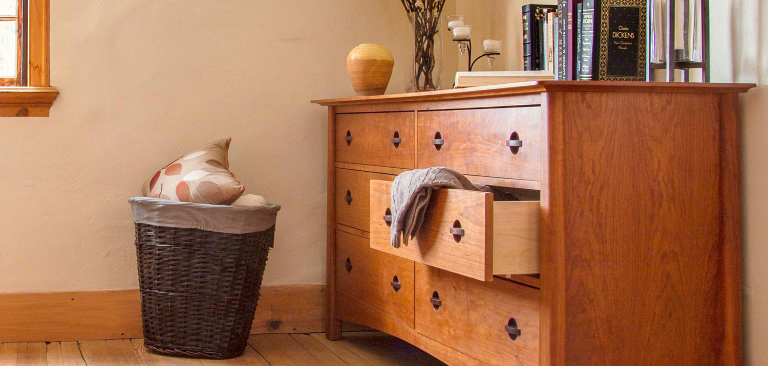 A wooden dresser in a room with a window.