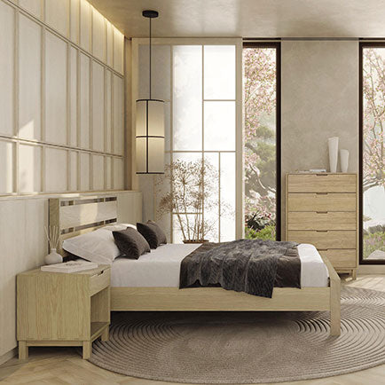 A modern bedroom features a wooden bed with white and brown bedding, a matching wooden nightstand, and a chest of drawers. Tall windows showcase a scenic outdoor view. A round rug lies under the bed, and a contemporary light fixture hangs from the ceiling.